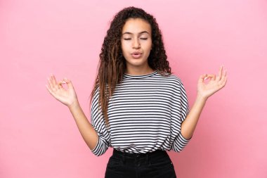 Zen pozisyonunda pembe arka planda izole edilmiş genç İspanyol kadın.