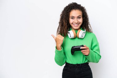 Young Arab woman playing with a video game controller isolated on white background pointing to the side to present a product clipart