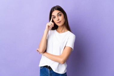 Kafkasyalı genç bir kadın mavi arka planda izole edilmiş bir fikir düşünüyor.