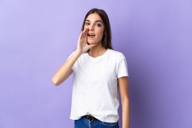 Mavi arka planda izole edilmiş genç beyaz kadın ağzı açık bağırıyor.