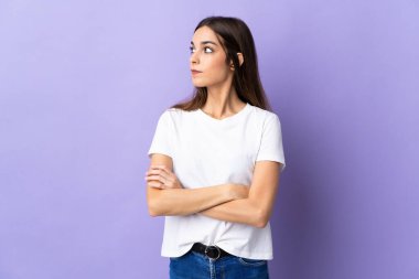 Mavi arka planda izole genç beyaz kadın kollarını çapraz tutuyor.