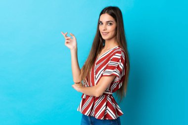 Mavi arka planda izole edilmiş genç, beyaz bir kadın var.