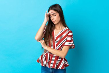 Kafkasyalı genç bir kadın mavi arka planda izole edilmiş, baş ağrısı var.