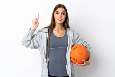 Beyaz arka planda izole edilmiş basketbol oynayan genç bir kadın harika bir fikre işaret ediyor.