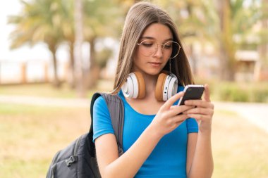 Dışarıdaki genç kız cep telefonu kullanıyor.