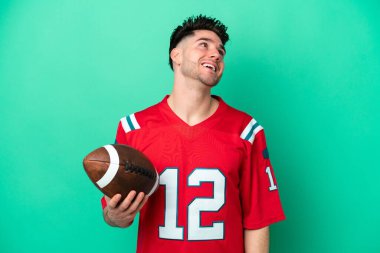 Rugby oynayan beyaz bir adam yeşil arka planda izole edilmiş gülüyor.