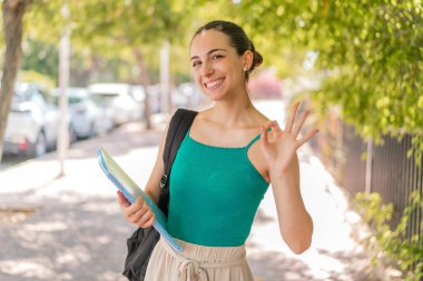 Dışarıdaki güzel bayan öğrenci parmaklarıyla işaret veriyor.