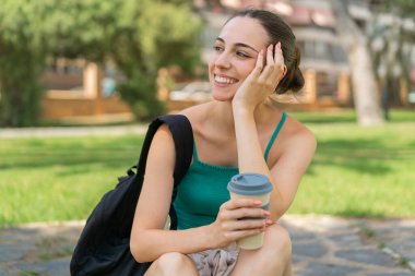 Dışarıdaki güzel kadın elinde kahve tutuyor.
