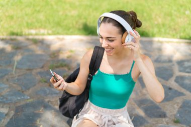 Dışarıda cep telefonu kullanan genç ve güzel bir kadın.