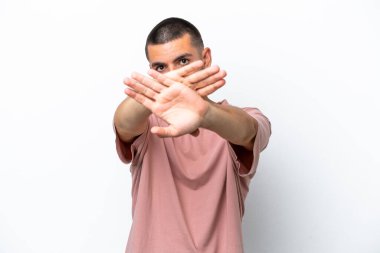 Beyaz arka planda izole edilmiş genç beyaz bir adam bir eylemi durdurmak için eliyle jesti durduruyor.