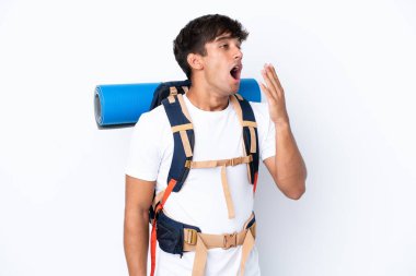 İzole edilmiş beyaz arka planda büyük bir sırt çantası olan genç dağcı kadın esniyor ve ağzını eliyle kocaman açık tutuyor.