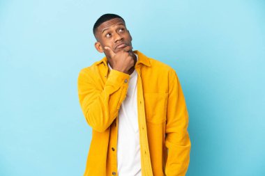 Mavi arka planda izole edilmiş genç latin adamın şüpheleri var.