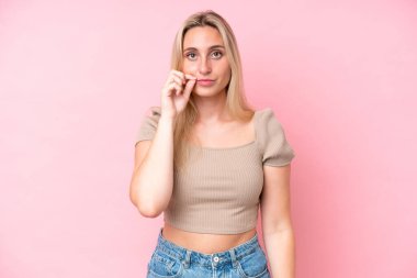 Pembe arka planda izole edilmiş beyaz bir kadın sessizlik işareti gösteriyor.