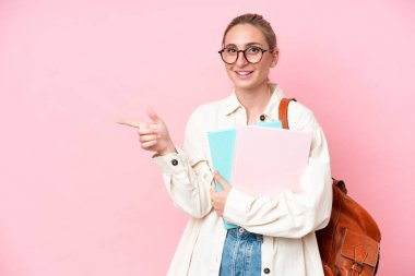 Pembe arka planda izole edilmiş genç beyaz bir kadın parmak işareti yapıyor.