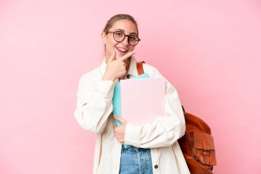 Pembe arka planda izole edilmiş genç beyaz kadın mutlu ve gülümsüyor.