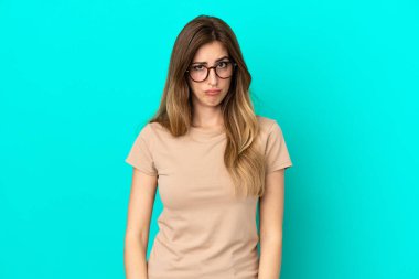 Mavi arka planda, üzgün bir ifadeyle izole edilmiş beyaz bir kadın.