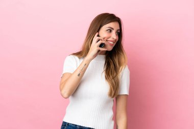 Pembe arka planda izole edilmiş beyaz bir kadın cep telefonuyla sohbet ediyor.