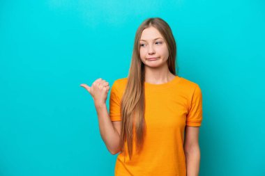 Young Russian woman isolated on blue background unhappy and pointing to the side