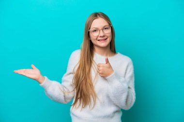 Mavi arka planda izole edilmiş genç bir Rus kadın. Avucunun içinde hayali bir şey tutuyor. Bir ilan vermek için.