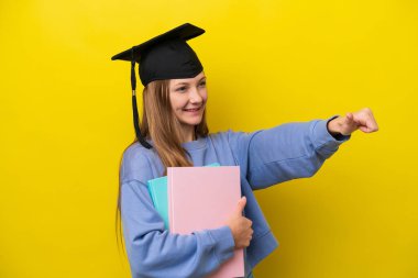 Genç Rus öğrenci, sarı arka planda izole edilmiş bir şekilde baş parmak işareti yapıyor.