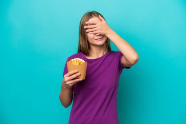 Patates kızartması yakalayan genç Rus kadın mavi arka planda izole edilmiş gözlerini elleriyle kapatıyor. Bir şey görmek istemiyorum.
