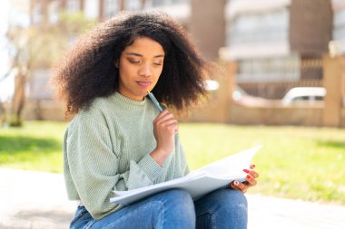 Genç Afrikalı Amerikalı bir kadın elinde bir defter tutuyor.