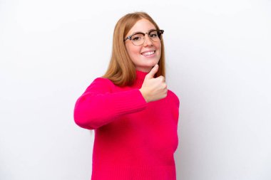 Beyaz arka planda izole edilmiş genç, kızıl saçlı bir kadın baş parmak işareti yapıyor.