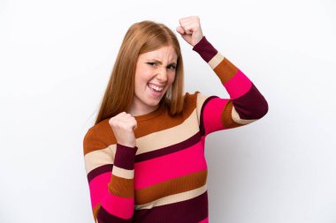 Genç kızıl saçlı kadın beyaz arka planda izole edilmiş zaferi kutluyor.