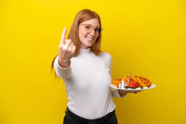 Sarı arka planda gözleme tutan kızıl saçlı genç bir kadın geliyor.