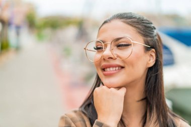 Genç ve güzel bir kadın gözlüklü ve düşünürken yukarı bakıyor.