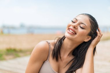 Genç, güzel bir kadın açık havada, mutlu bir ifadeyle.