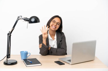 Genç iş karışık ırktan kadın ofiste mutlu çalışıyor ve parmaklarıyla dört tane sayıyor.