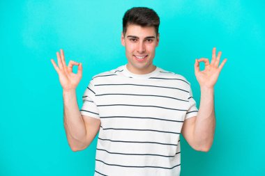 Zen pozisyonunda mavi arka planda izole edilmiş genç beyaz bir adam.