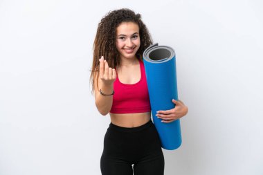 Genç spor yapan Arap kadın yoga derslerine giderken beyaz arka planda izole edilmiş bir minder tutuyor ve para hareketi yapıyor.