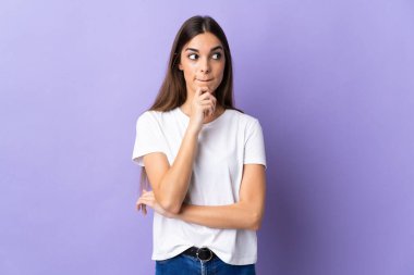 Kafkasyalı genç bir kadın mavi arka planda izole edilmiş. Şüpheleri ve düşünceleri var.