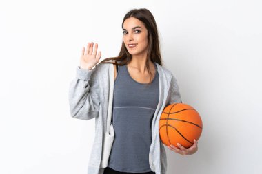 Basketbol oynayan genç bir kadın, beyaz arka planda soyutlanmış, mutlu bir ifadeyle selamlanıyor.