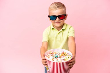 Küçük Rus çocuk izole bir arka planda büyük bir kasede patlamış mısır yiyor.