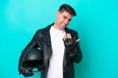 Motosiklet kasklı genç, beyaz bir adam mavi arka planda izole edilmiş, bizimle gelmesi için davet ediliyor. Gelmene sevindim.