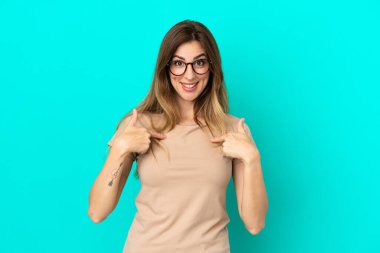 Mavi arka planda yalıtılmış beyaz bir kadın. Şaşırtıcı bir yüz ifadesi var.