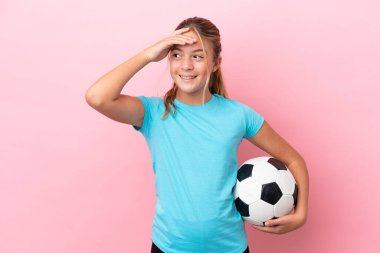 Küçük futbolcu kız pembe arka planda izole edilmiş, çok gülümsüyor.
