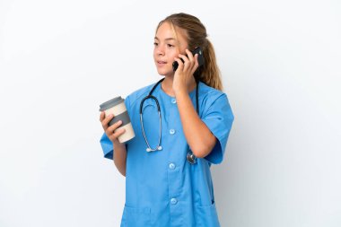 Cerrah kılığına girmiş küçük beyaz bir kız. Beyaz arka planda izole edilmiş. Elinde kahve ve cep telefonu var.