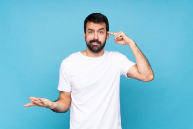 Mavi arka planda sakallı genç adam deliliğin jestini yapıyor. Parmağını kafaya koyuyor.