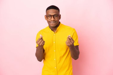 Pembe arka planda izole edilmiş genç Latin adam para hareketi yapıyor.