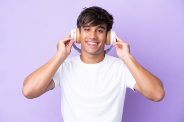 Mor arka planda izole edilmiş genç beyaz adam müzik dinliyor.
