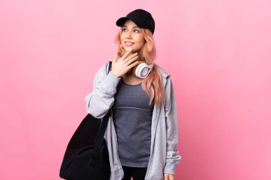 Spor çantalı genç bayan izole edilmiş arka planda gülümserken yukarı bakıyor.