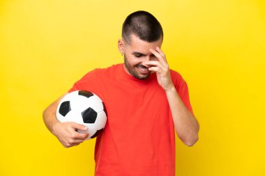 Young caucasian man playing soccer isolated on yellow background laughing