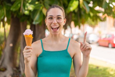 Dışarıda kornet dondurması olan genç ve güzel bir kadın harika bir fikri işaret ediyor.