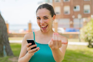 Açık havada cep telefonu kullanan genç ve güzel bir kadın. Gelmene sevindim.