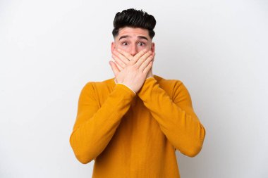 Beyaz arka planda izole edilmiş genç beyaz bir adam elleriyle ağzını kapatıyor.