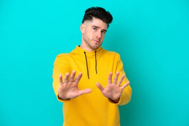 Kafkasyalı genç adam mavi arka planda izole edilmiş gergin eller öne doğru uzanıyor.